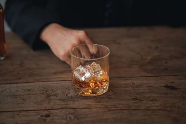 男子端着一杯白兰地，他正在酒吧里喝白兰地，饮酒损害驾驶能力，还会损害健康。喝酒的概念图片下载
