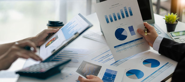 业务同事使用笔记本电脑和分析技术分析纸质文件、账目、合同、投资顾问、企业营销计划上的财务数据。图片下载