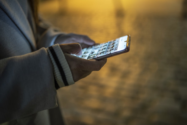 在城市的夜晚，女人拿着手机。城市打破。图片下载