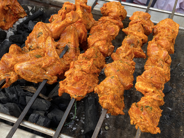 全画幅图片的生鸡肉串，腌制的生鸡胸肉块在金属串，躺在热木炭余烬排，抬高的观点图片下载