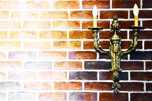 青铜金色的烛台在明亮的红色砖墙上，明亮的文字空间图片下载
