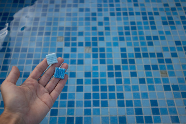 手握游泳池地板上的小瓷砖。损坏的游泳池图片下载