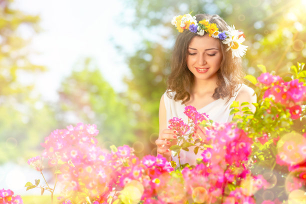 童话形象艺术照片。户外特写年轻美丽快乐微笑幻想女人的肖像。年轻的女神在明媚的阳光和粉红色的玫瑰中享受着春天的自然图片下载