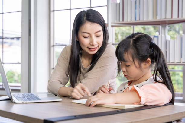 家庭教育病毒大流行期间在家学习。一名亚洲妇女和她的女儿在客厅里，戴着外科口罩以保护她们免受病毒感染。图片下载