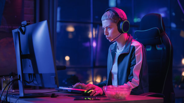 兴奋的女玩家在电脑上玩在线视频游戏。戴着耳机的女性在PvP锦标赛中与其他玩家战斗，通过麦克风与团队交谈。图片下载