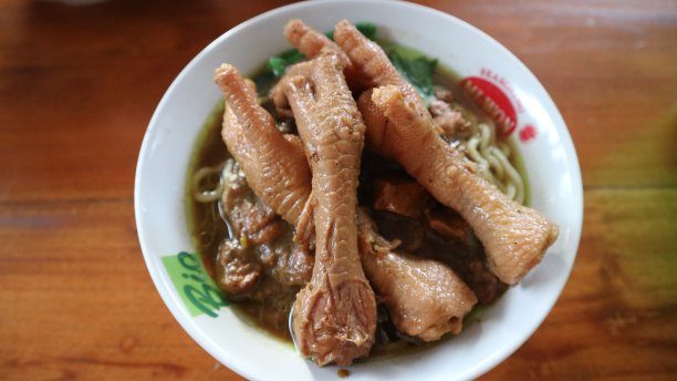 在木桌上的白色碗里的Mie ayam Ceker。鸡肉面配美味的鸡爪，印尼街头小吃包括面条、蔬菜、鸡肉和鸡爪。图片下载