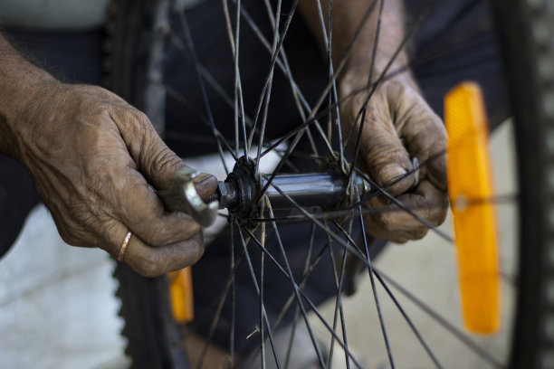 一位老人用手指在服务店用工具近距离修理摩托车轮胎图片下载