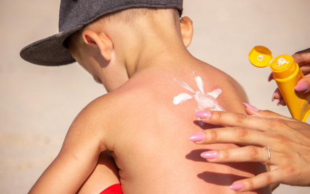 妈妈把防晒霜涂在她蓝色的背上。图片下载