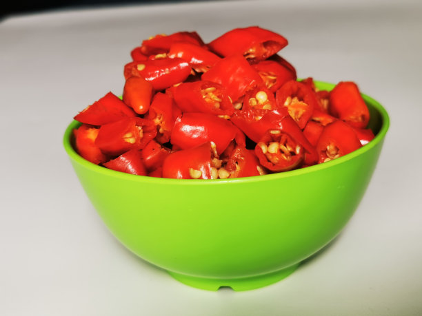 一束印尼红辣椒(辣椒)，切碎后放入白色背景的绿色碗中图片下载