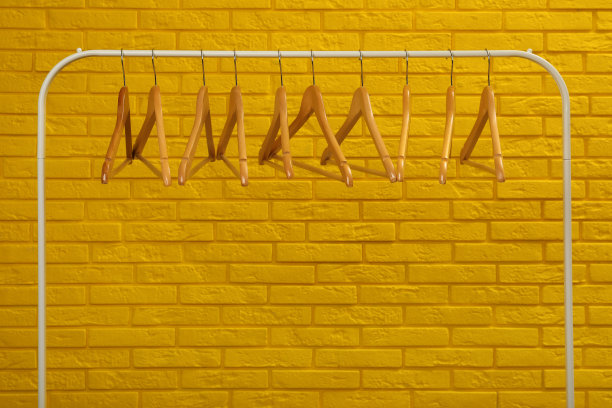黄色砖墙附近有许多衣架的衣柜架图片下载