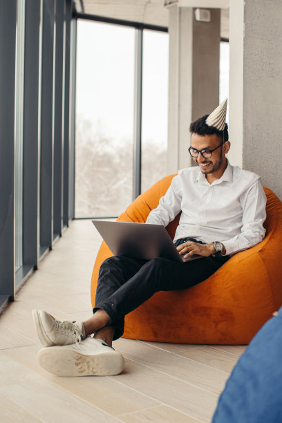 庆祝完生日后，一名年轻的印度男子在办公室里用笔记本电脑工作。在办公室庆祝生日的概念图片下载