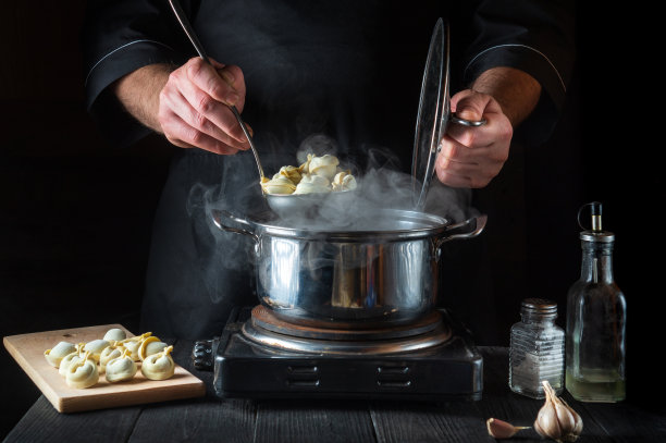 厨师在餐厅厨房里用平底锅准备意大利饺子。特写的厨师手，而工作图片下载