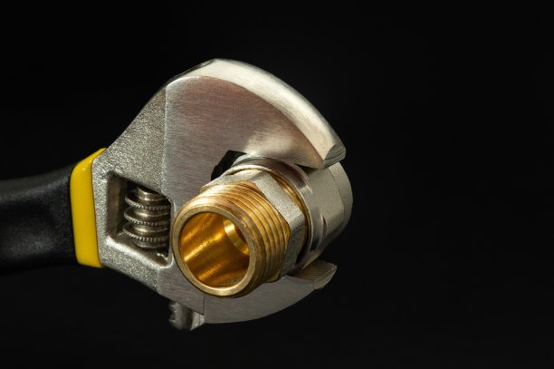 黑色背景黄铜配件的活动扳手。水管维修方案图片下载