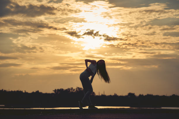观看海上日落的年轻女子剪影。令人惊叹的自然背景。带有复制空间的色调照片。图片下载
