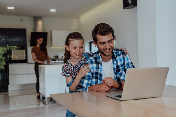 父亲和女儿在现代化的房子里，在假期和他们的家人在笔记本电脑上聊天。现代家庭的生活图片下载