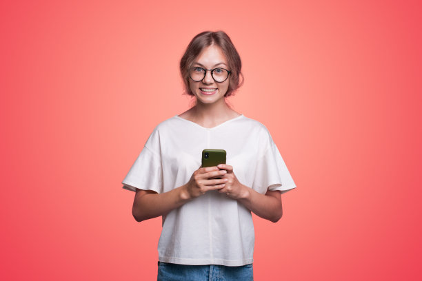 照片中的一个积极的情绪惊讶的年轻女子发送信息与手机孤立的粉红色背景。快乐的生活方式。社交媒体信息。粉红色的背景。图片下载