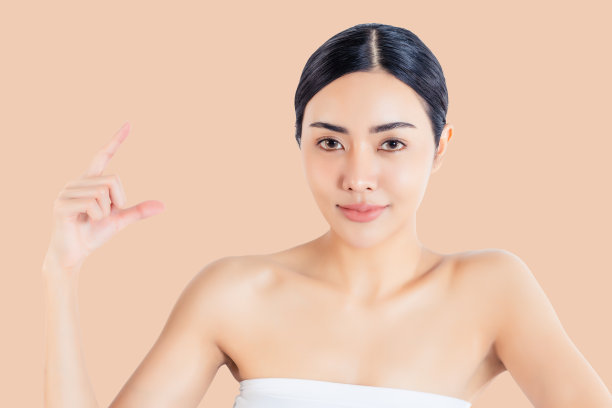 画像年轻美丽的亚洲女子与发光的皮肤隔离在米色背景上想象复制空间在她的手上插入广告护肤概念用于美容皮肤护肤水疗的广告图片下载