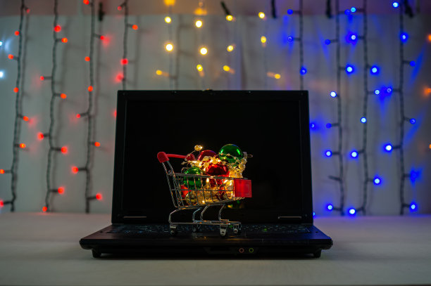 笔记本电脑键盘上有圣诞球和花环的购物车。图片下载