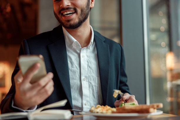 午餐时间，身穿西装的印度商人微笑着在咖啡馆打电话图片下载