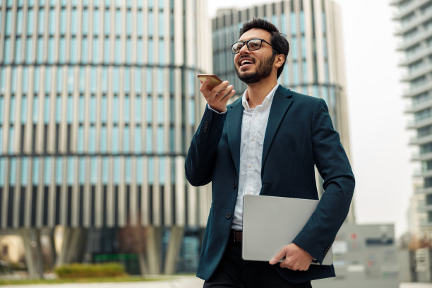 印度商人用笔记本电脑在休息时站在办公室附近给客户录音图片下载
