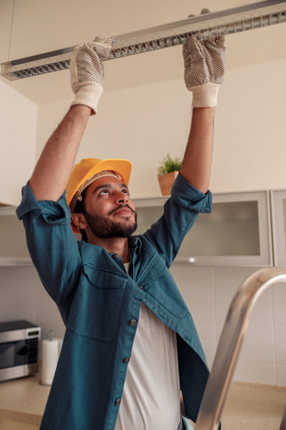穿着制服的专业电工工人正在厨房安装电灯图片下载