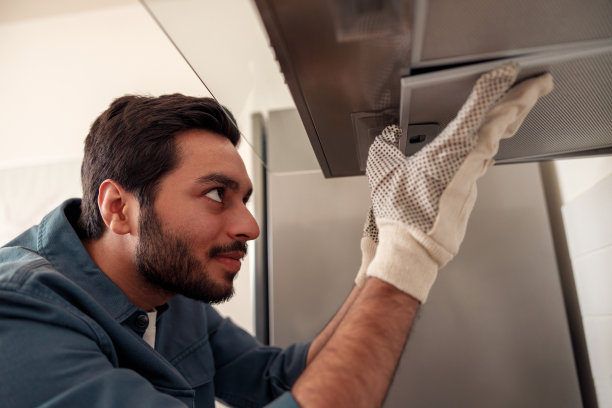 勤杂工穿着制服修理厨房抽油机，更换灶具罩过滤器。维护的概念图片下载