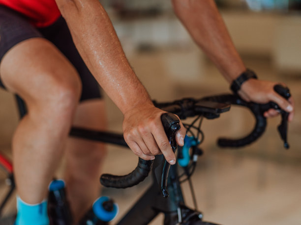 特写照片的人骑铁人三项自行车的机器模拟在一个现代客厅。在大流行条件下进行培训。图片下载