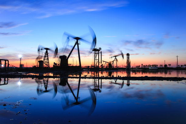 傍晚，油田现场，油泵正在运转，油泵和美丽的夕阳倒映在水中图片下载