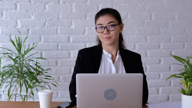 该公司的一名员工坐在笔记本电脑前从事办公活动。坐着的桌子是必不可少的东西，因为工作直接关系到员工的工作场所。图片下载