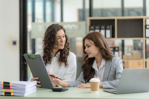 年轻有魅力的白人老板兼助理，在办公室的桌子上放着图纸和平板电脑，听着金融业务咨询图片下载