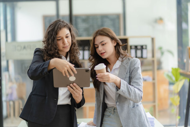 年轻有魅力的白人老板兼助理，在办公室的桌子上放着图纸和平板电脑，听着金融业务咨询图片下载
