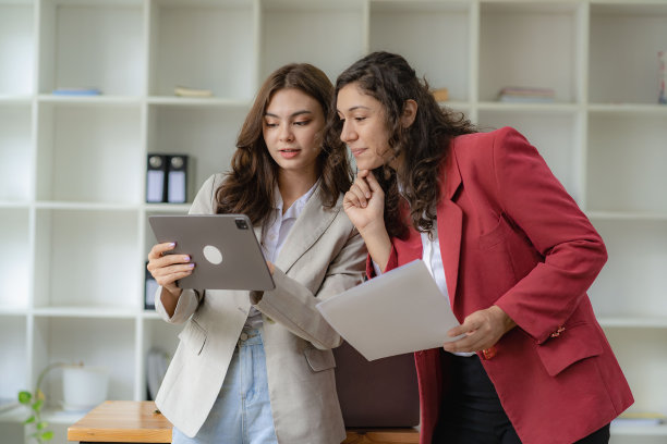 年轻有魅力的白人老板兼助理，在办公室的桌子上放着图纸和平板电脑，听着金融业务咨询图片下载