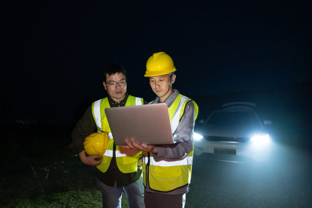 晚上，两名男性工程师用笔记本电脑在风力发电场工作图片下载