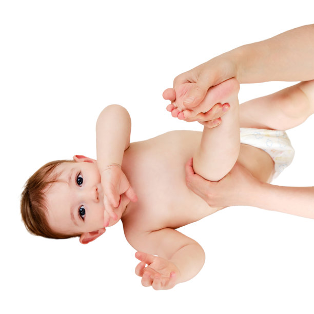 一位母亲正在给一个被孤立在白色背景上的蹒跚学步的婴儿按摩。妈妈的手正在揉孩子的腿，孤立在白色的背景上。一岁儿童图片下载