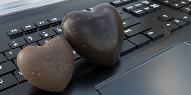 笔记本电脑键盘背景上的巧克力糖果心形。情人节庆祝活动。三维渲染图片下载