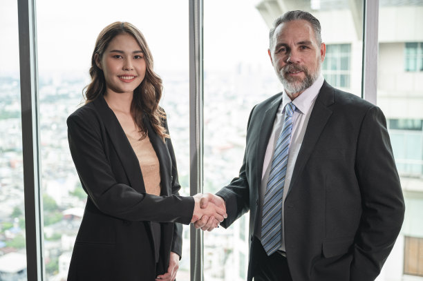 亚洲女商人在办公室与高级商人握手图片下载