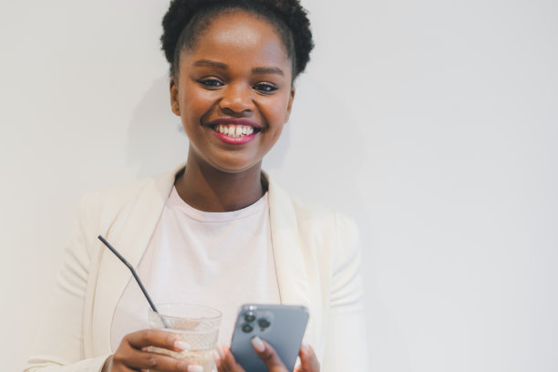 积极年轻的非洲妇女微笑着看短信站在咖啡咖啡馆。使用的概念。互联网技术。图片下载