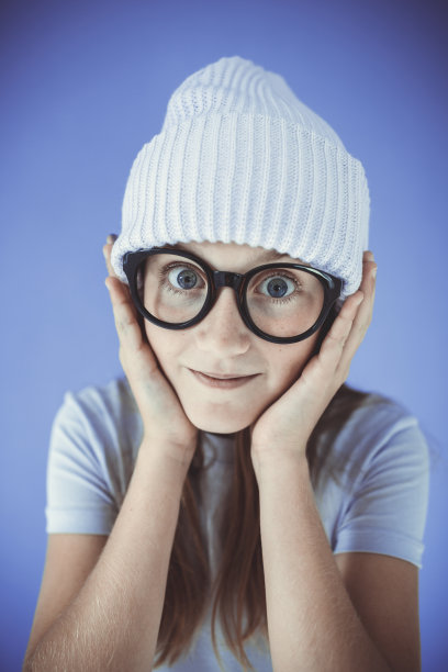 年轻的女孩，戴着厚厚的眼镜和无檐便帽图片下载