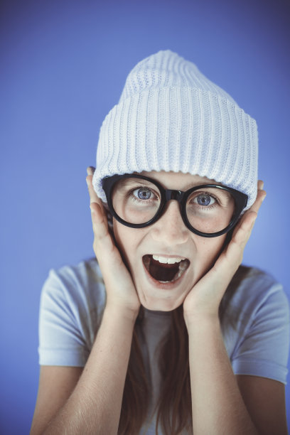年轻的女孩，戴着厚厚的眼镜和无檐便帽图片下载