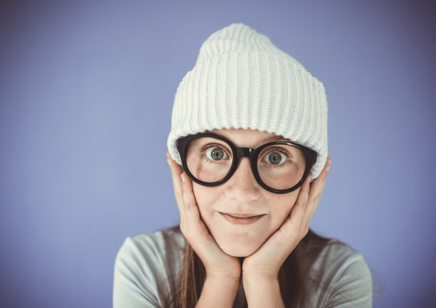 年轻的女孩，戴着厚厚的眼镜和无檐便帽图片下载