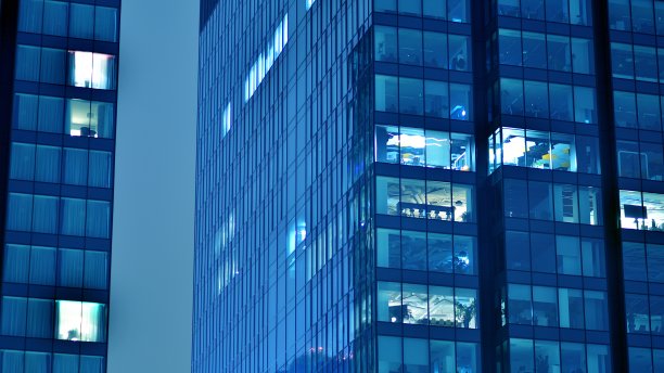 图案的办公楼窗户在夜间照明。图片下载