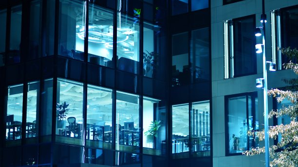 图案的办公楼窗户在夜间照明。图片下载