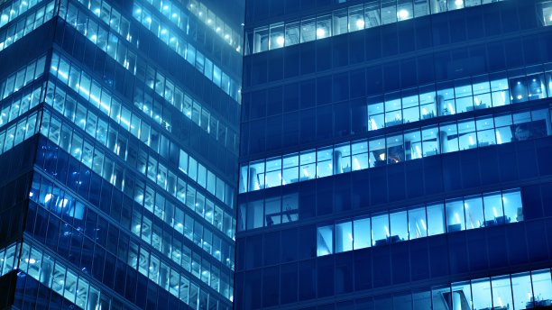 图案的办公楼窗户在夜间照明。图片下载