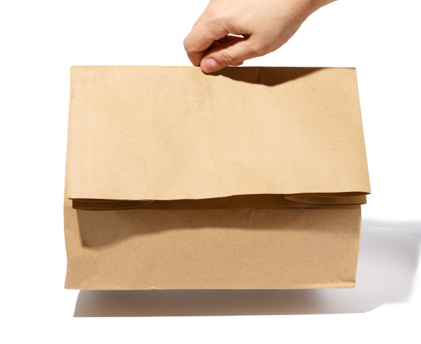 女性手拿一个白色背景的棕色纸袋图片下载