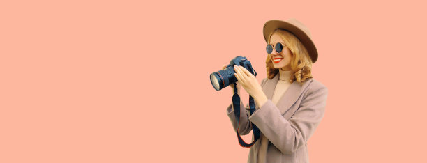 时尚快乐微笑的女摄影师与数码相机拍照，戴着圆帽子，棕色外套的背景，空白的复制空间为广告文字图片下载