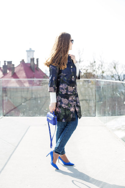 有女人味的女孩穿着蓝色的外套和包走在城市里，阳光明媚的天气图片下载