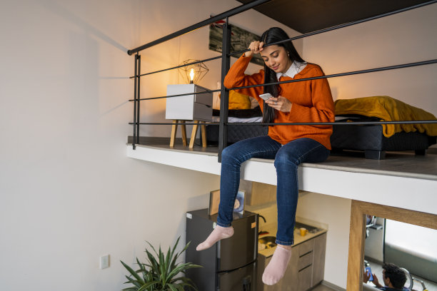 一位拉丁妇女坐在通往一楼的楼梯上，独自享受这一刻图片下载