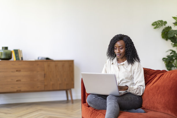 年轻的黑人妇女在家里用笔记本电脑工作图片下载