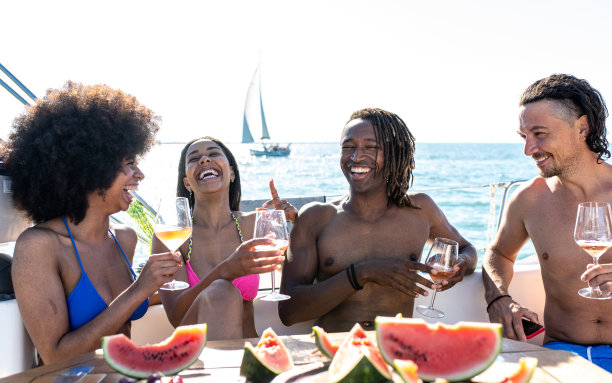 在游艇派对上，朋友们举杯祝酒，在游艇上，微笑的人们端着香槟，四个多种族的年轻朋友在一次豪华的航行中庆祝节日图片下载