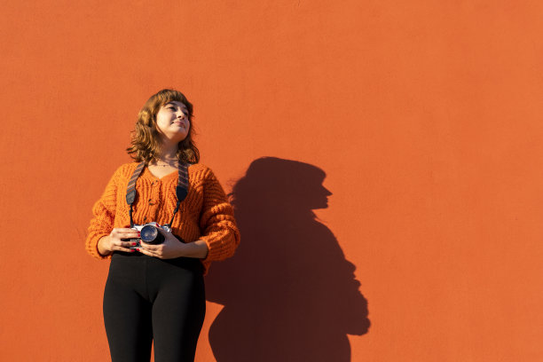 一个女人走过一堵橙色的墙图片下载